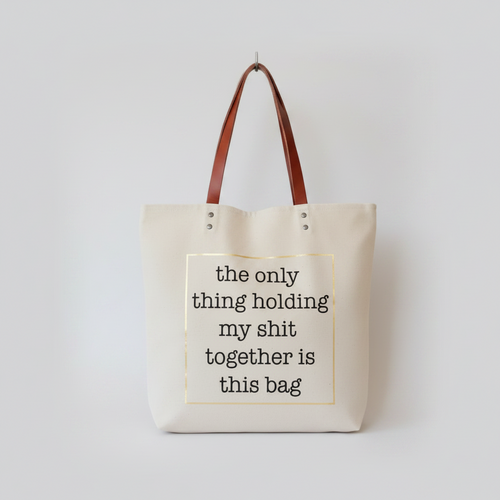 A beige canvas tote bag with brown leather handles.
